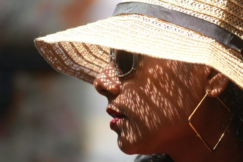 Mujer con sombrero de ala ancha y gafas de sol protegiendo el rostro del sol.